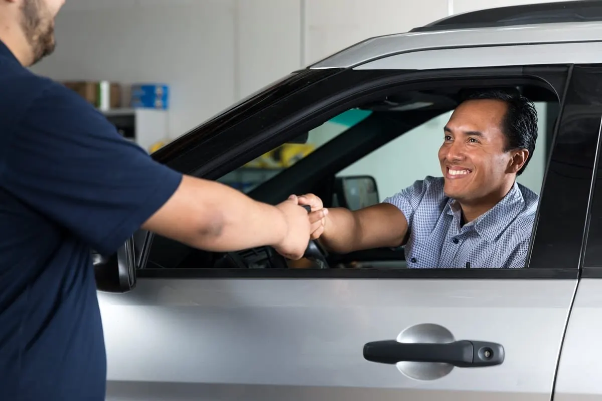 A driver hands his car keys to a technician at an ignition interlock service center.